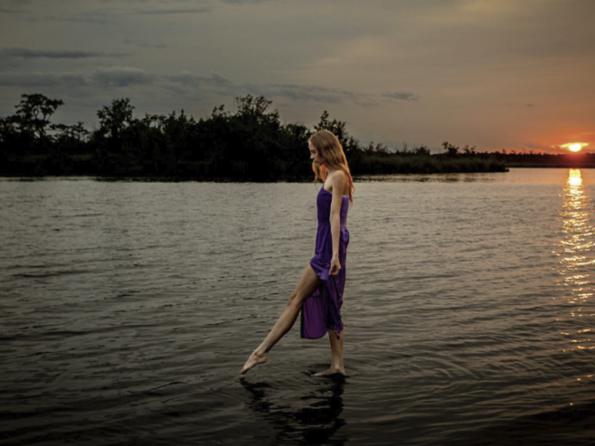 Creative portrait of a woman standing in the water at sunset