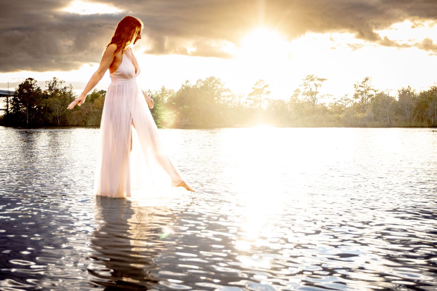 Creative portrait of a woman standing in the water at sunset