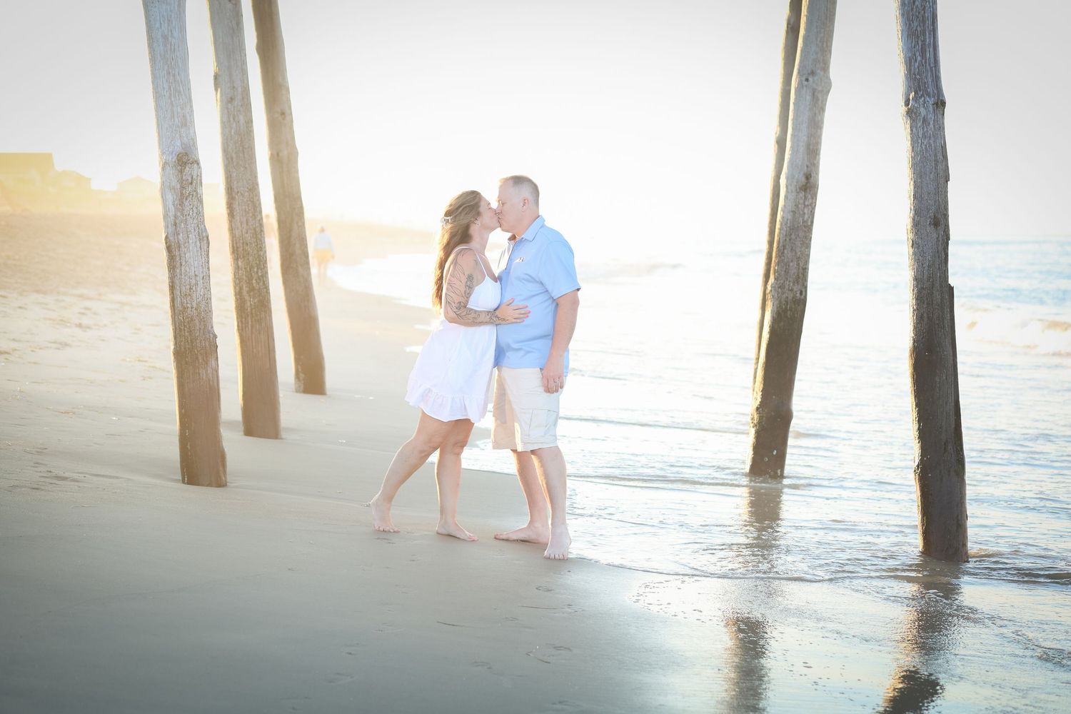 Couple embracing beneath a fishing pier on the beach