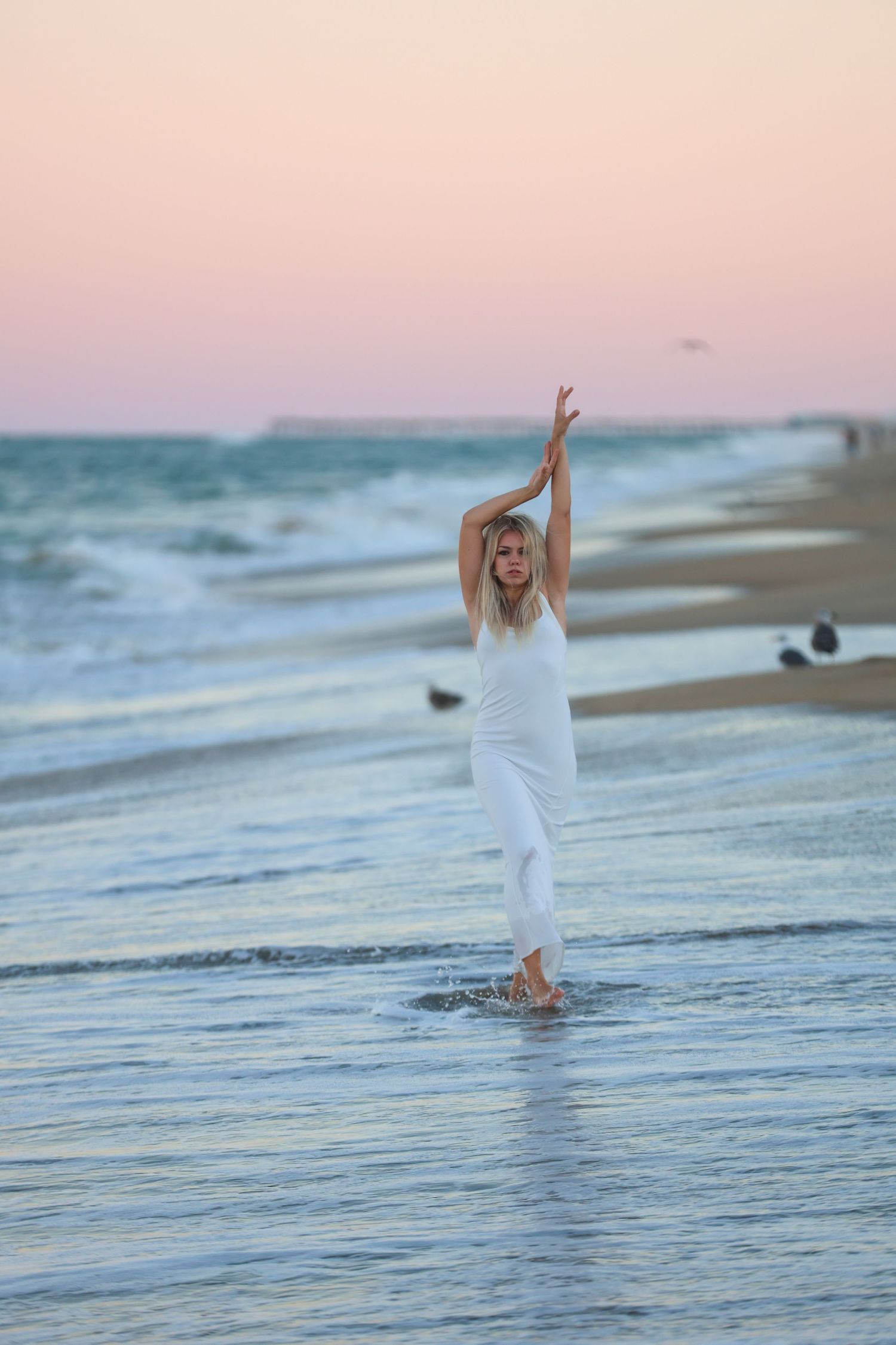 Creative beach portrait of a woman standing in the ocean at sunset