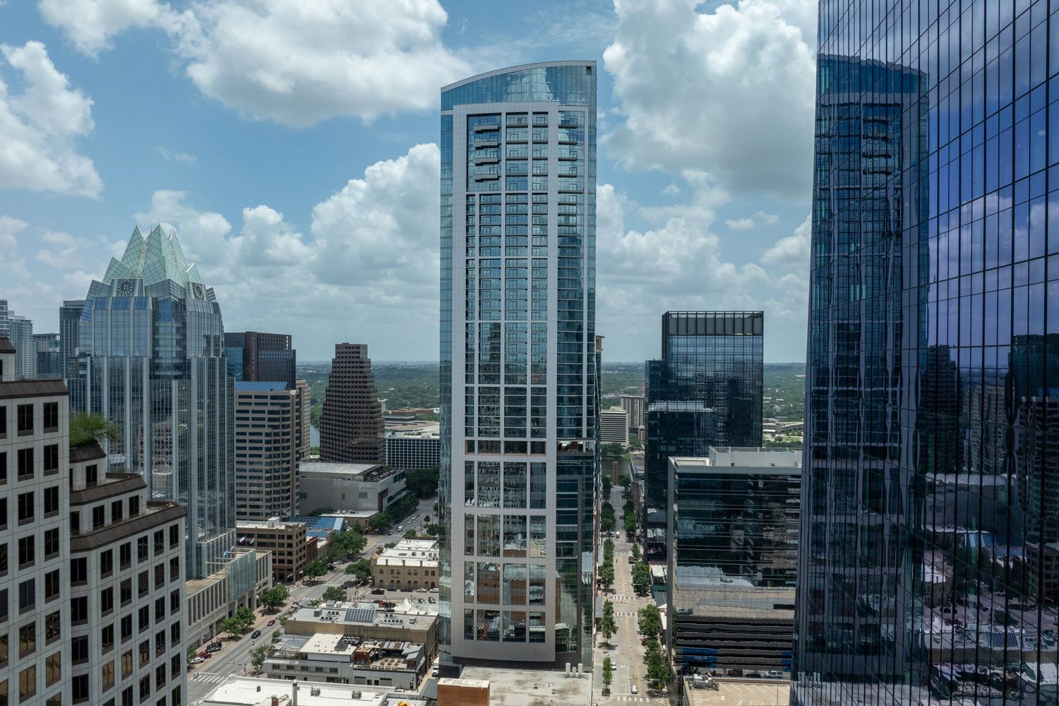 Aerial view of modern skyscrapers in downtown Austin, Texas, with blue glass towers under a partly cloudy sky.