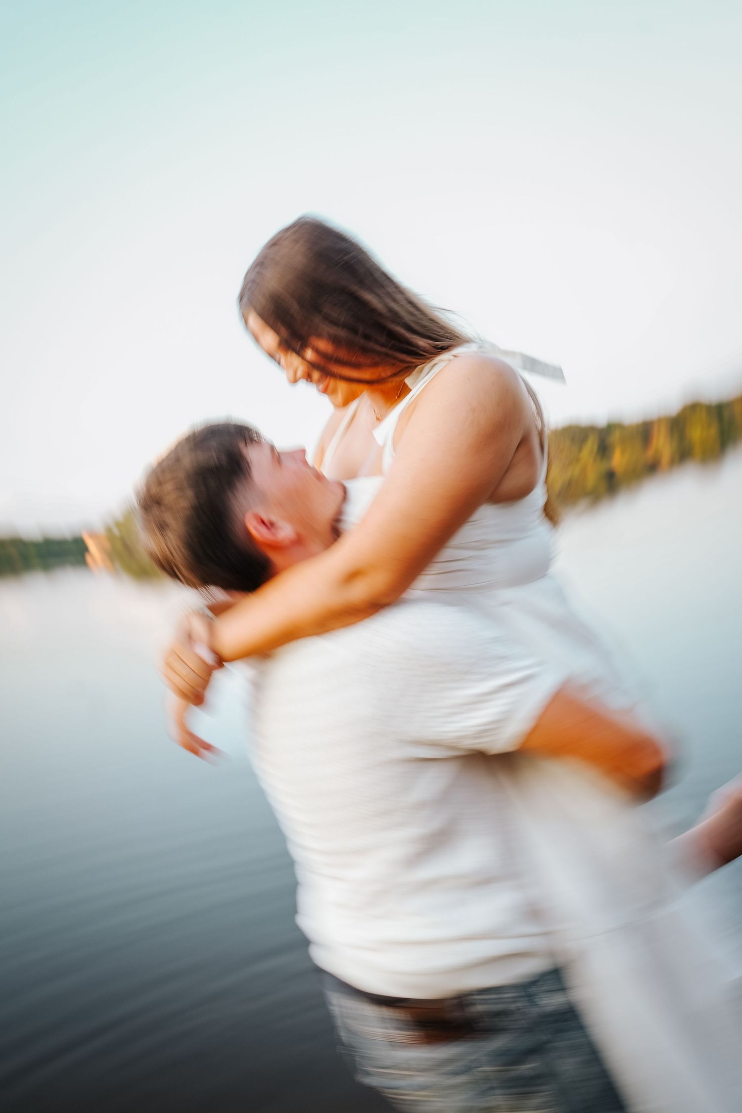 Couple shares a joyful spinning embrace in a lake with motion blur capturing the movement.