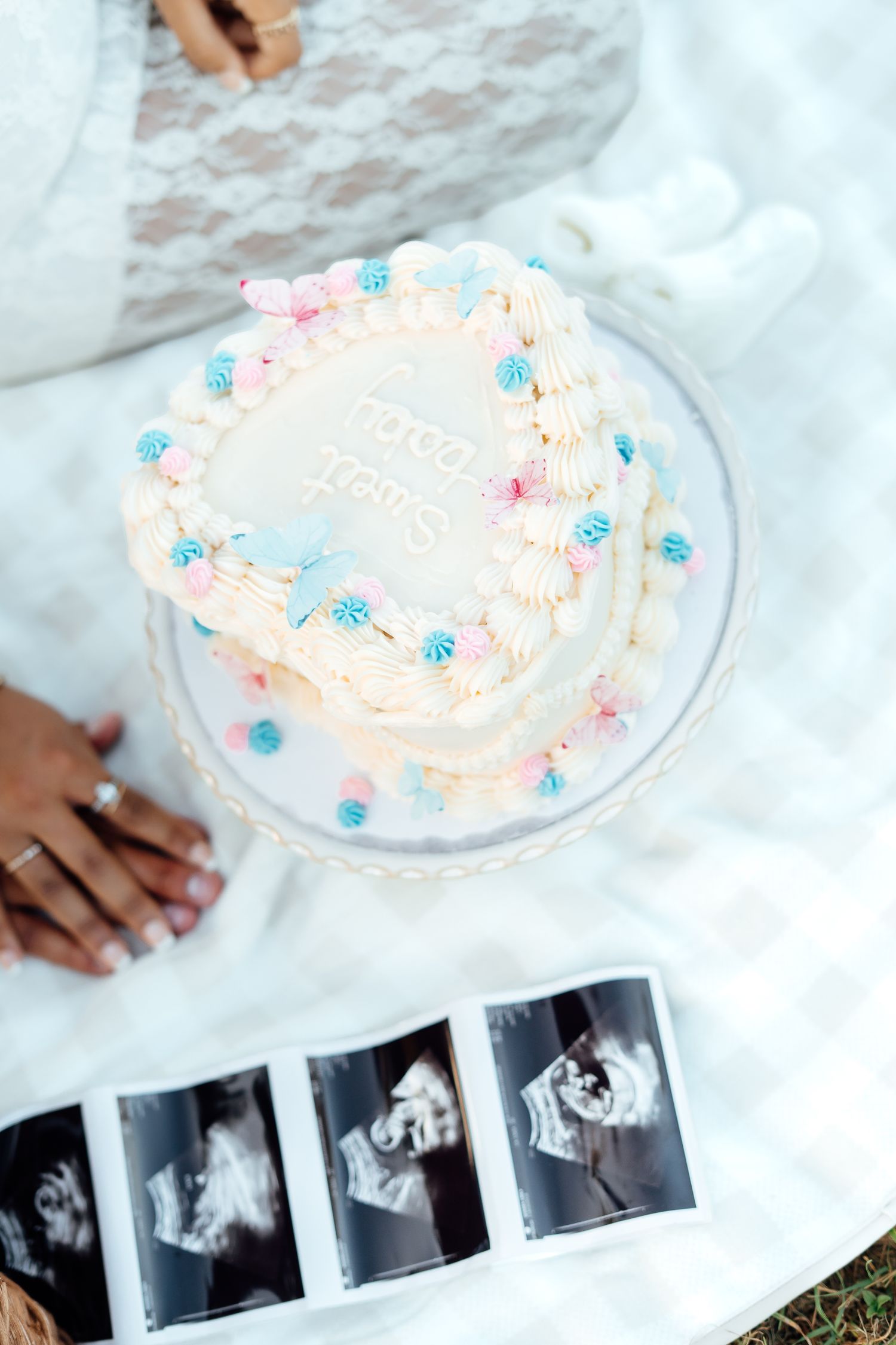 Top view of gender reveal cake with pink and blue decorations beside ultrasound photos.