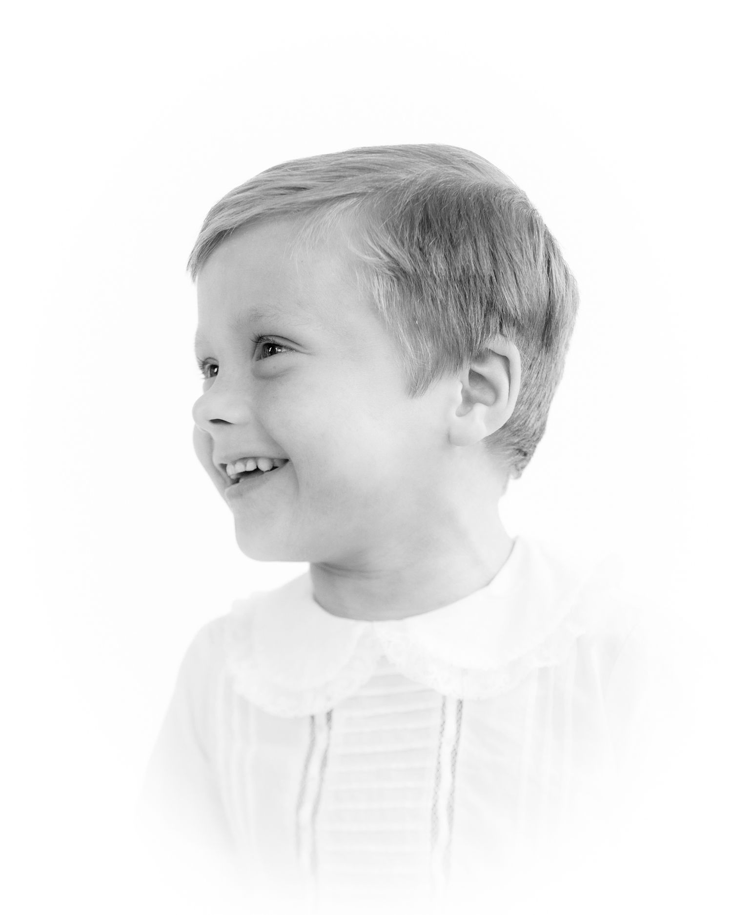 Laughing young boy in white shirt, black and white side profile portrait photography.