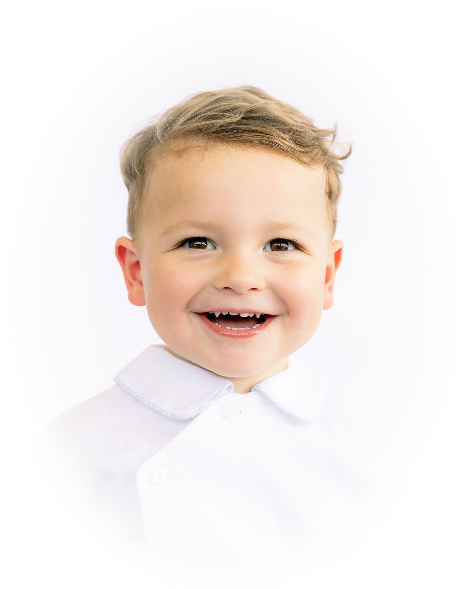 Cheerful toddler boy with big smile wearing white polo shirt, colorful studio portrait.