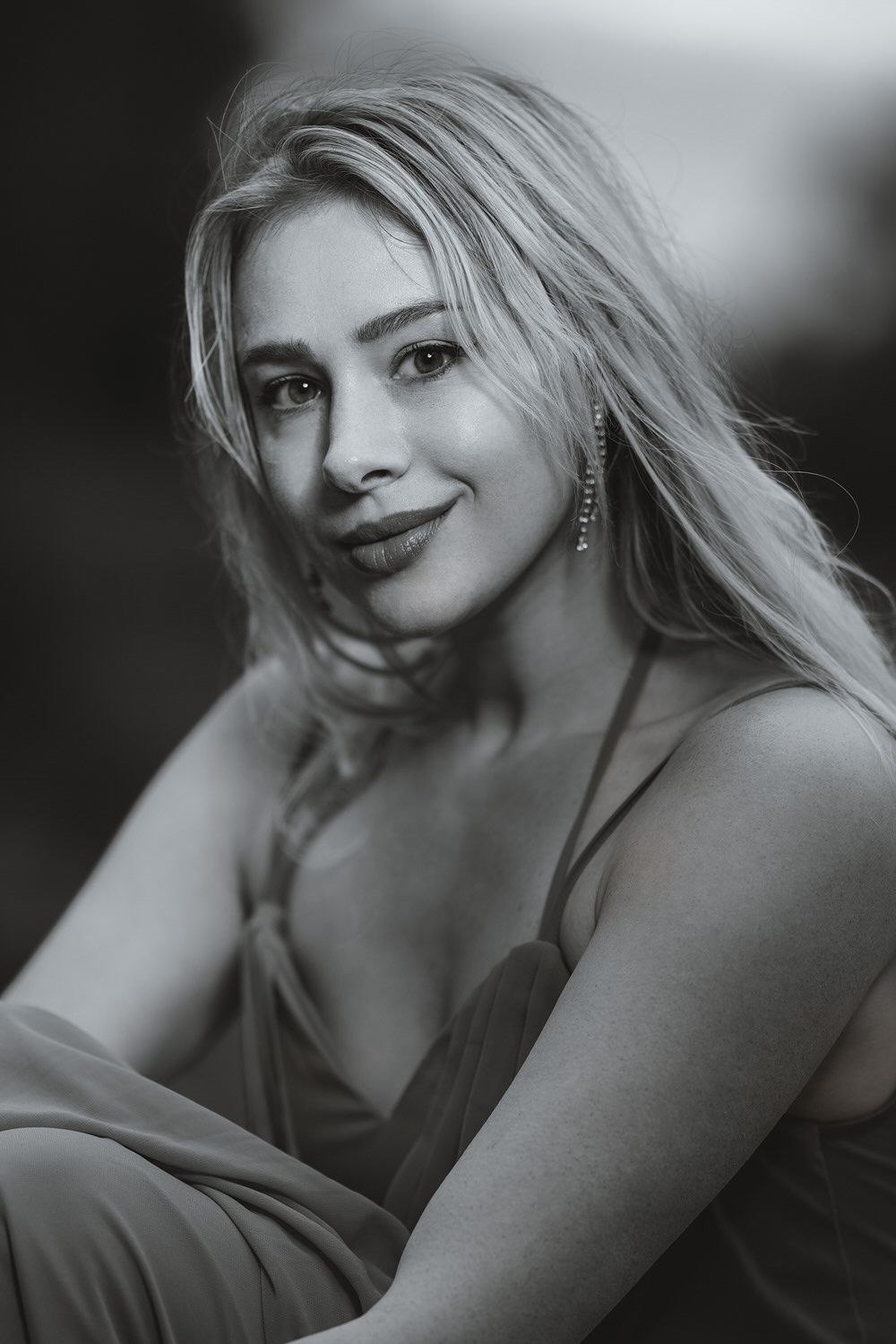 Elegant black and white portrait of a blonde woman in a dress smiling softly at the camera.