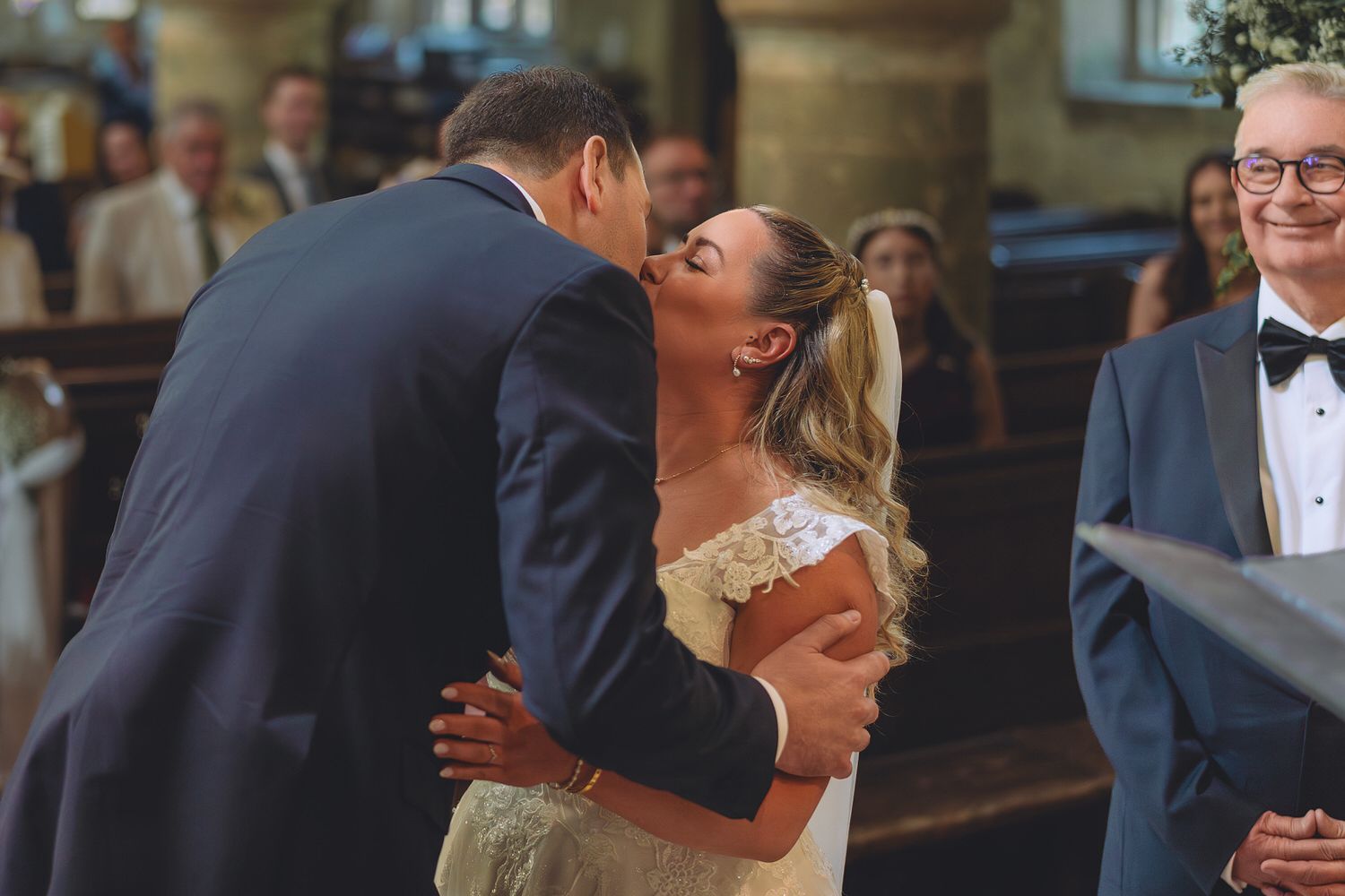Bride and groom sharing a heartfelt kiss at the altar during their wedding ceremony in a church.
