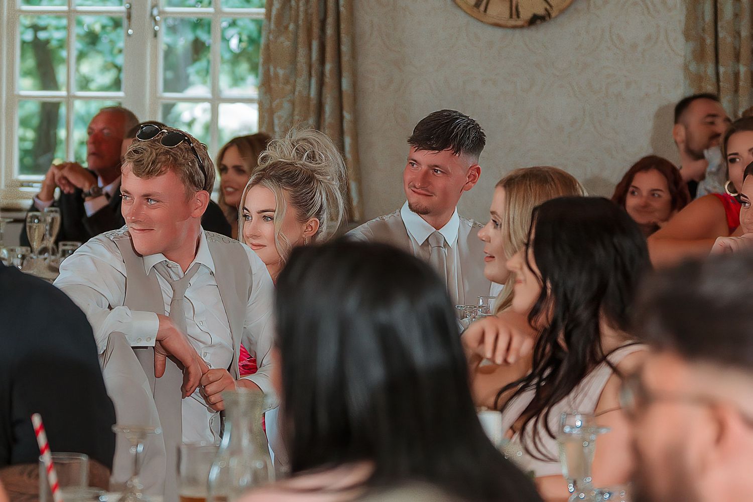 Wedding guests smiling and laughing together at a reception dinner in an elegant venue.