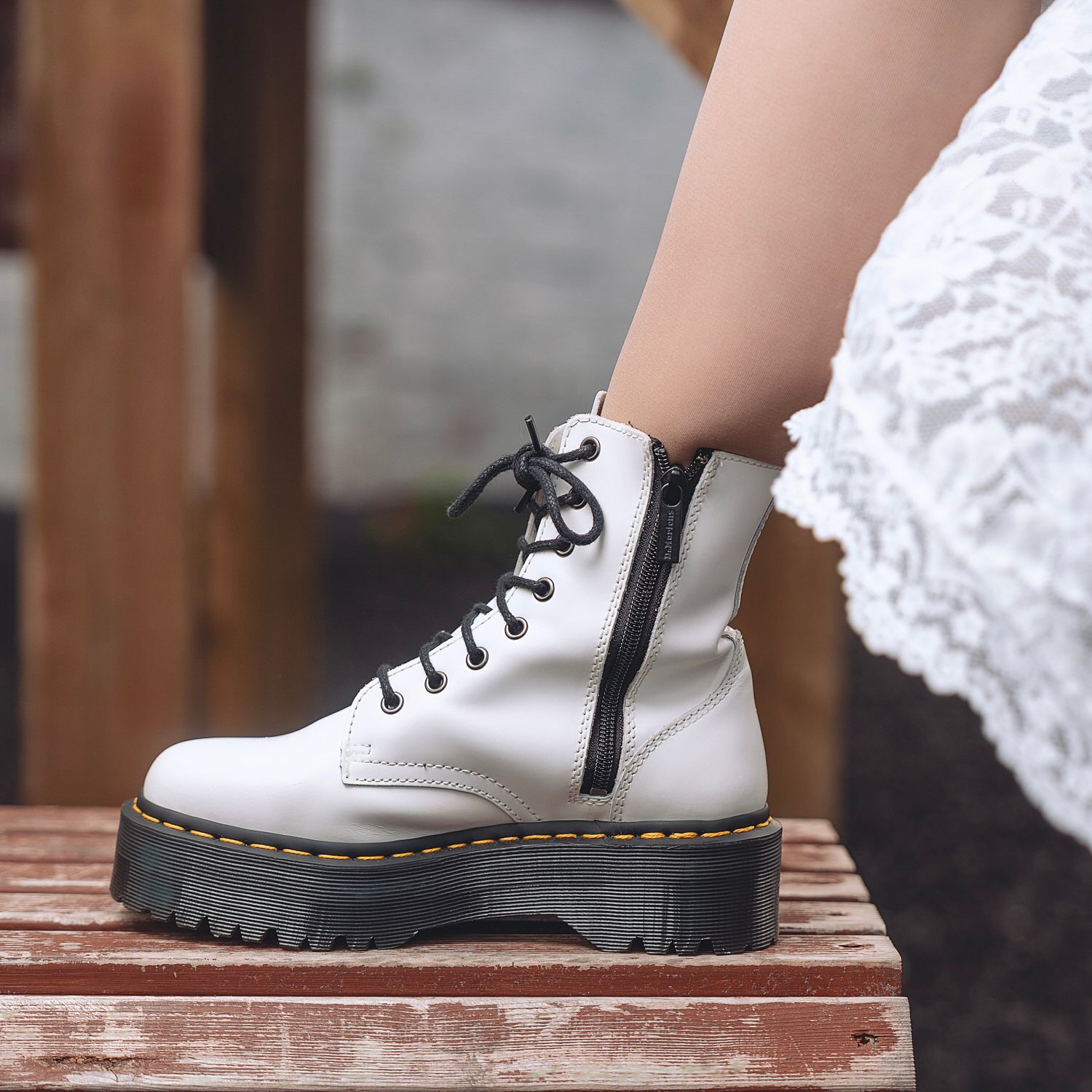 White platform lace-up ankle boots with side zipper, worn with a lace dress, showcasing chunky sole detail.