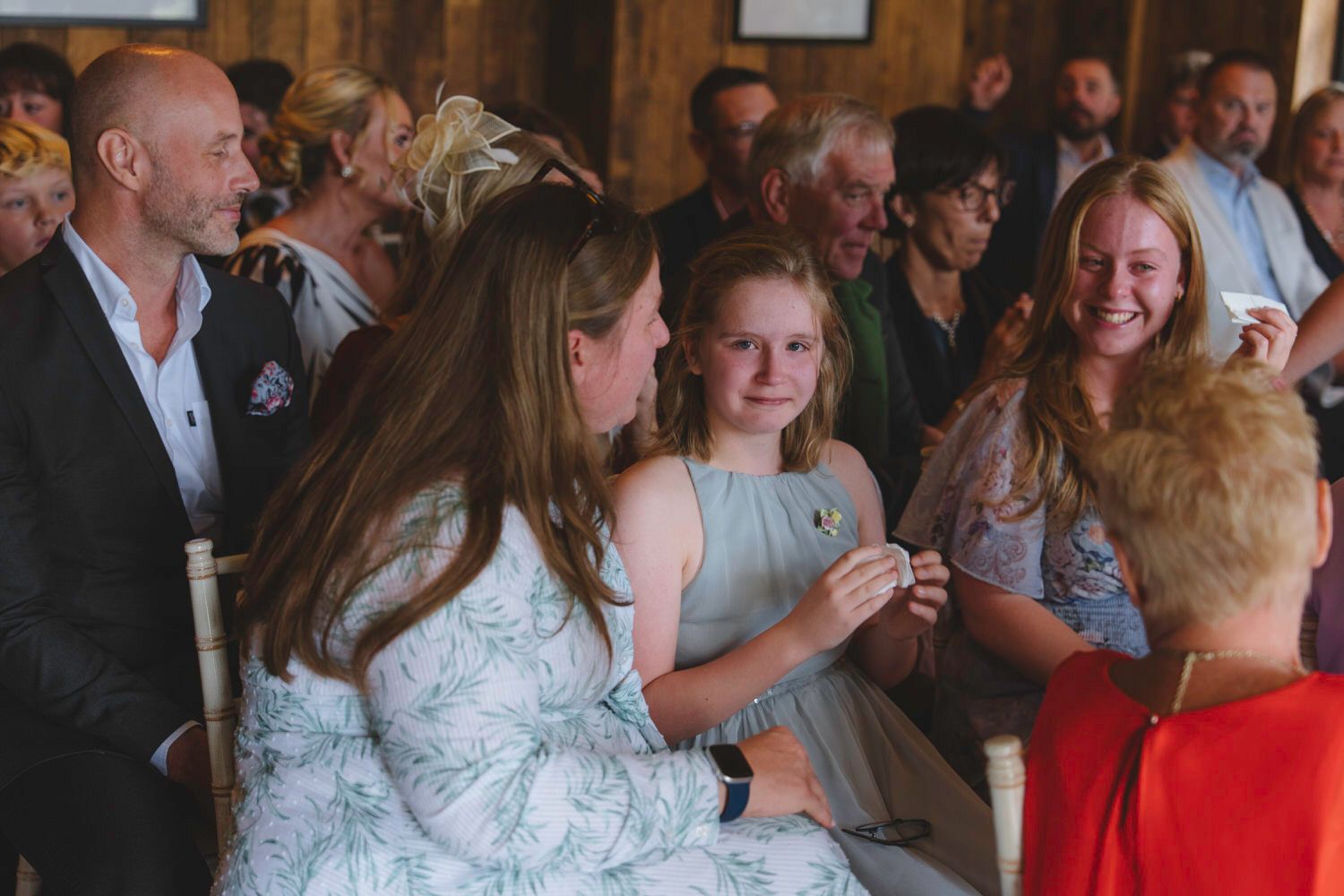 Guests laughing and sharing a joyful moment at a rustic wedding ceremony venue.