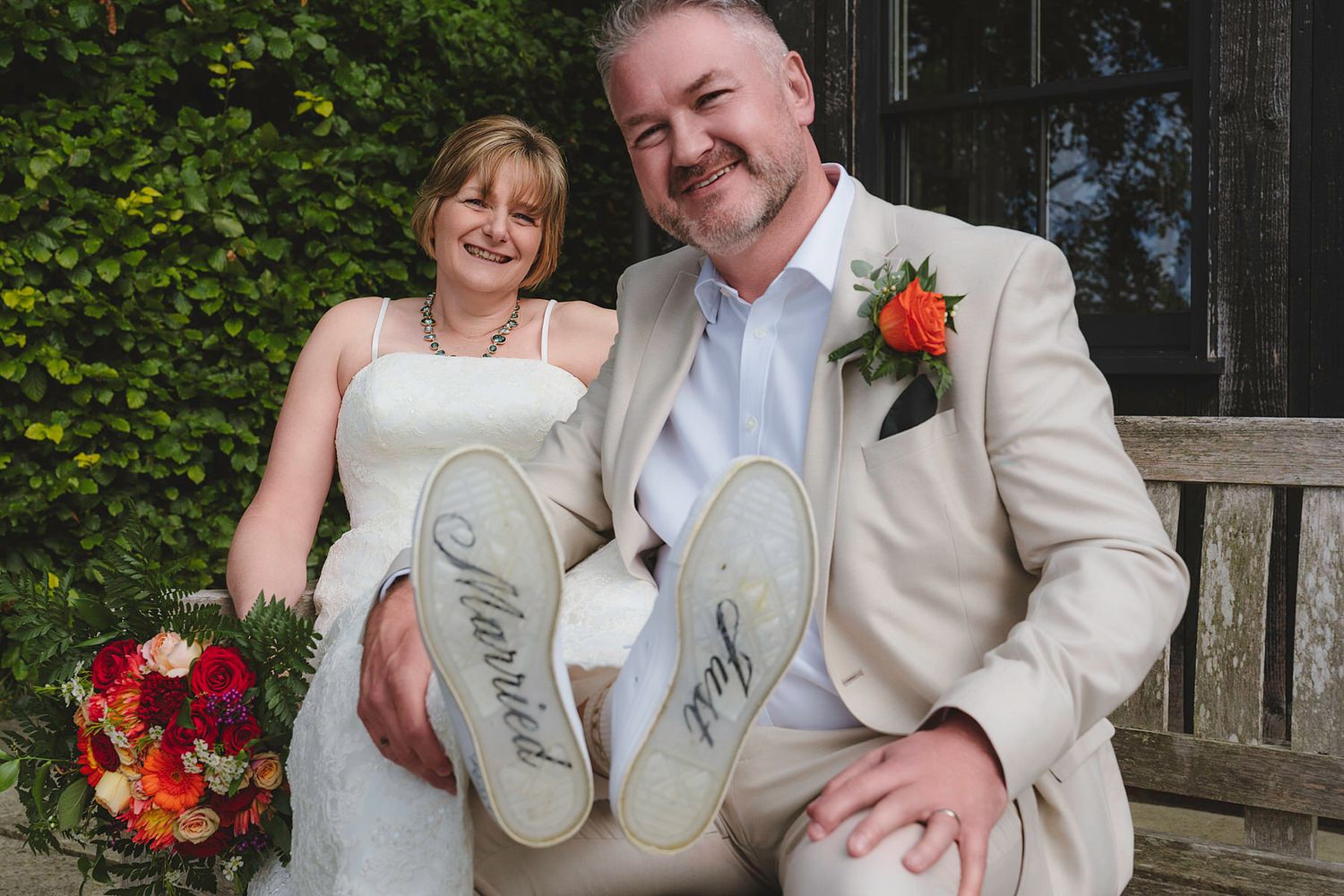 Smiling wedding couple showing customized sneakers reading Married and Just Wed.