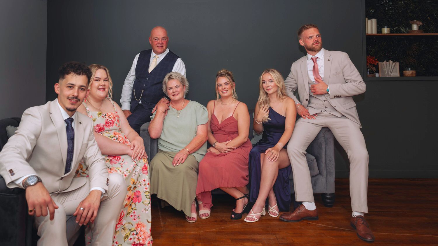 A cheerful family group of seven poses together in formal attire for a special occasion photo.