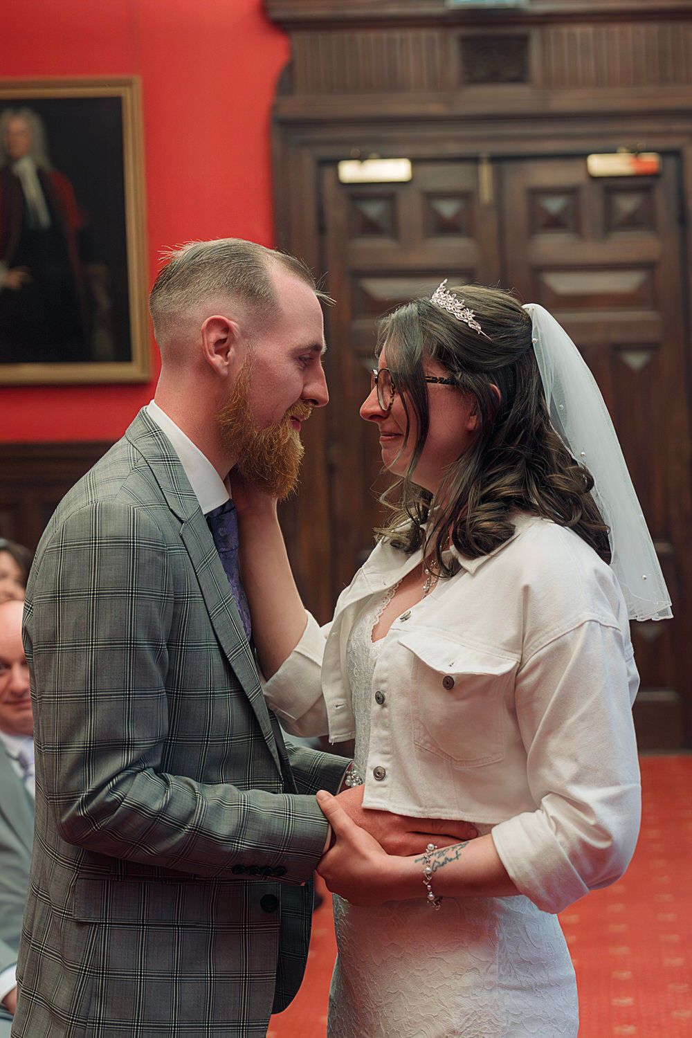 A bride and groom share an intimate moment during their wedding ceremony in an elegant wood-paneled venue.