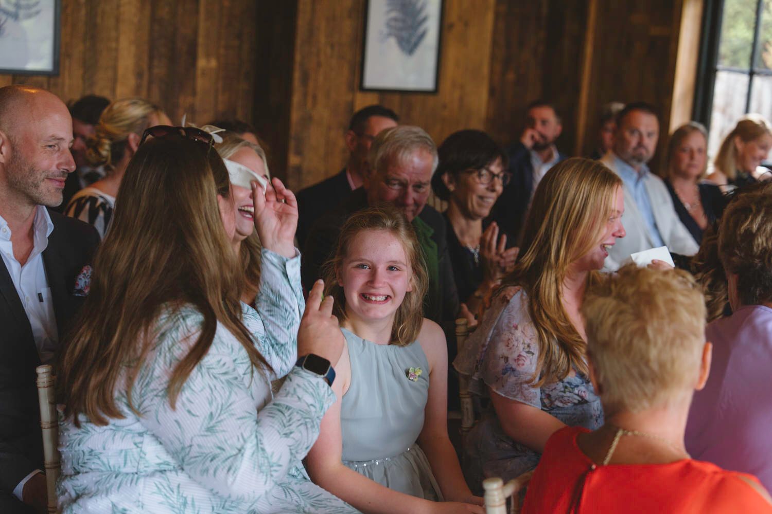 Guests laughing and smiling together at a wedding reception in a rustic venue.