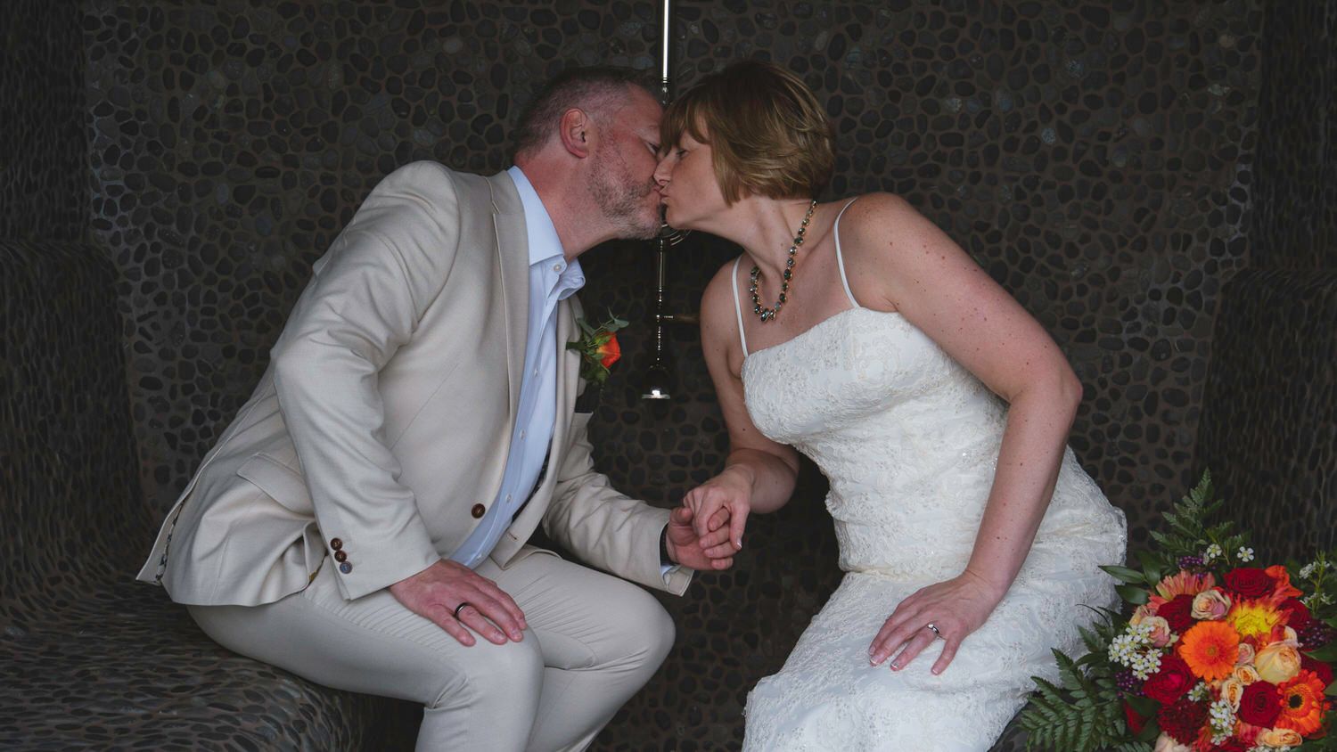 Bride and groom share a kiss while holding hands at their wedding ceremony.