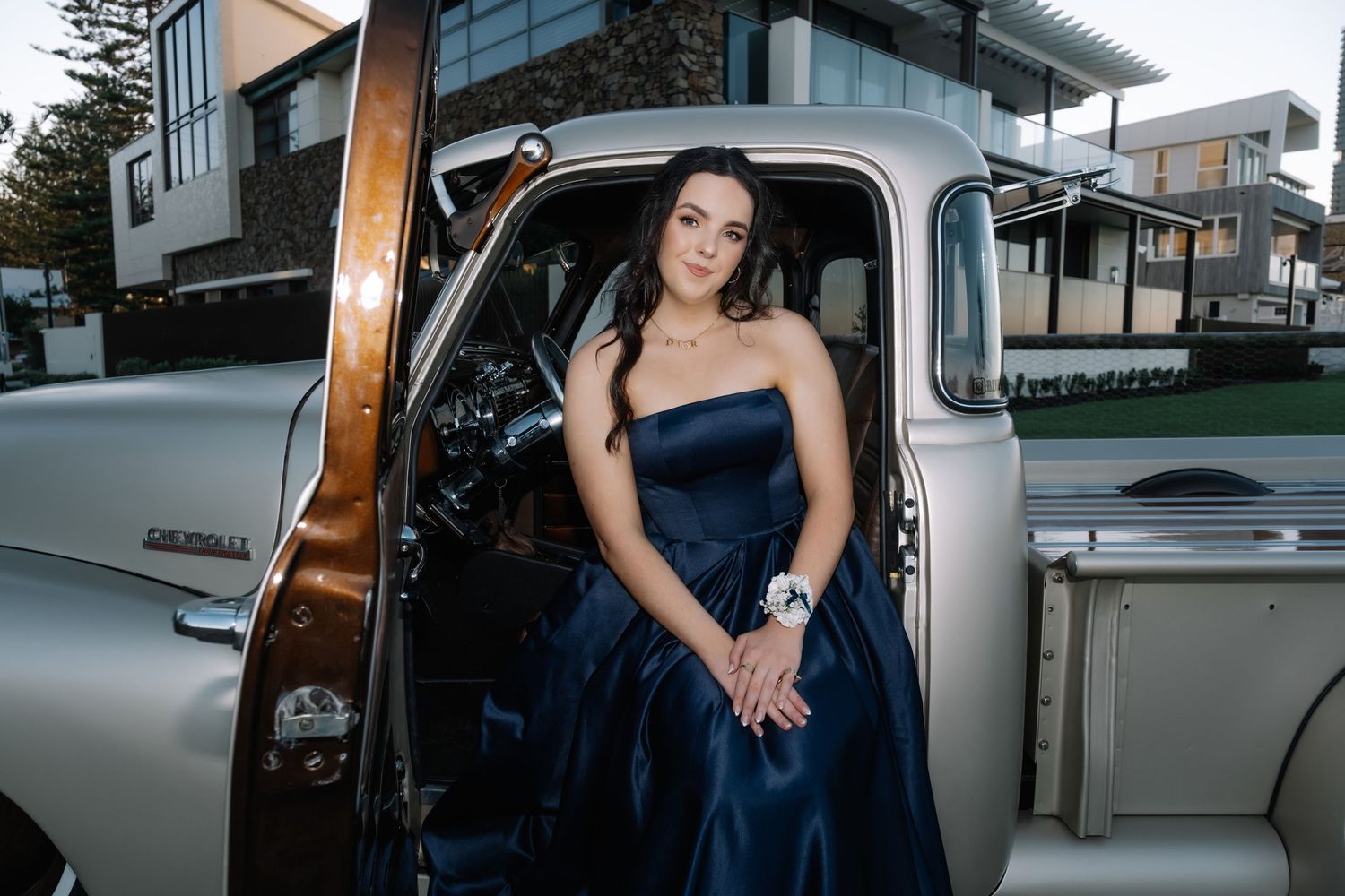 Young woman in navy strapless ball gown posing in vintage Chevrolet truck door.
