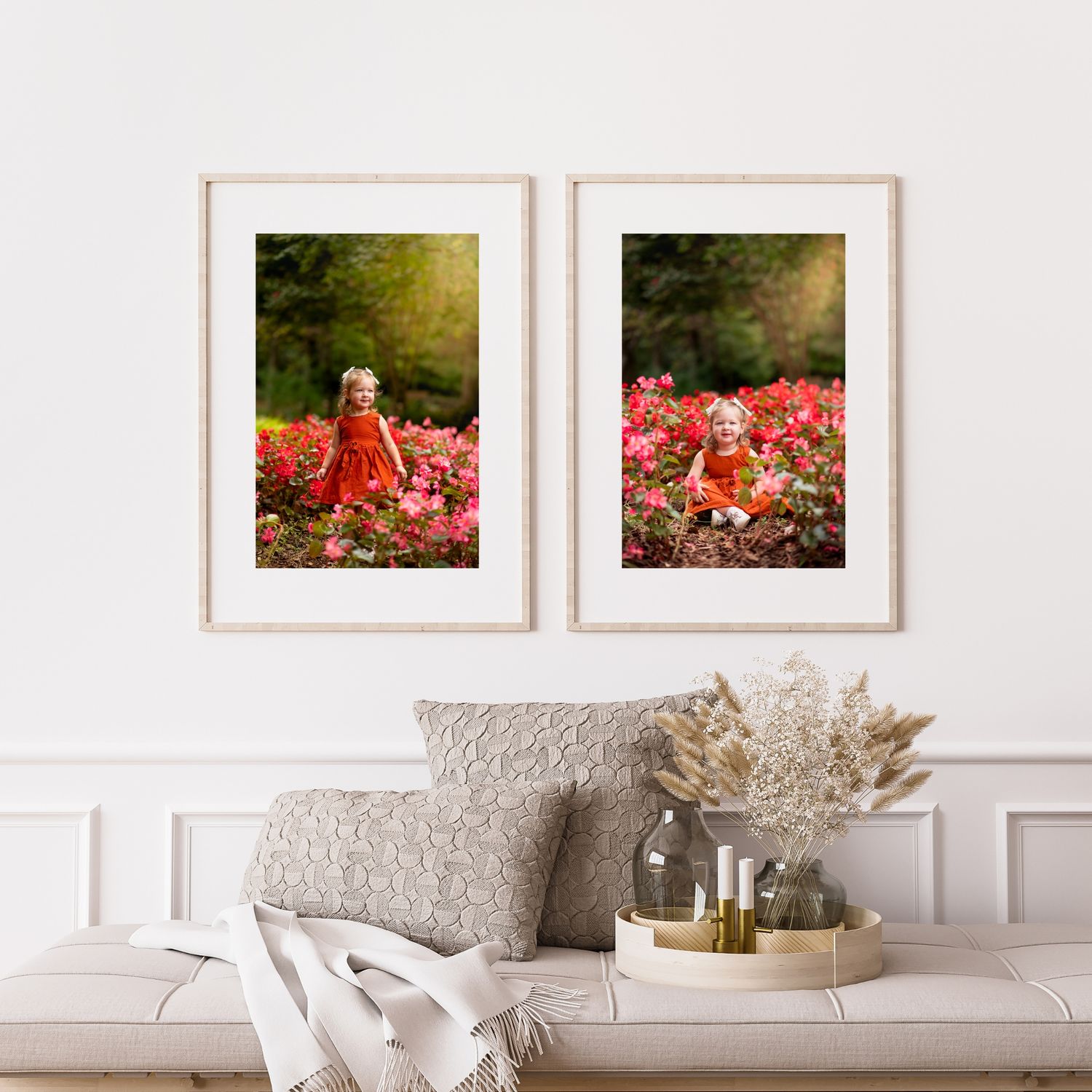 Two framed portraits of a young girl in a red dress among vibrant pink flowers hang above a sofa.