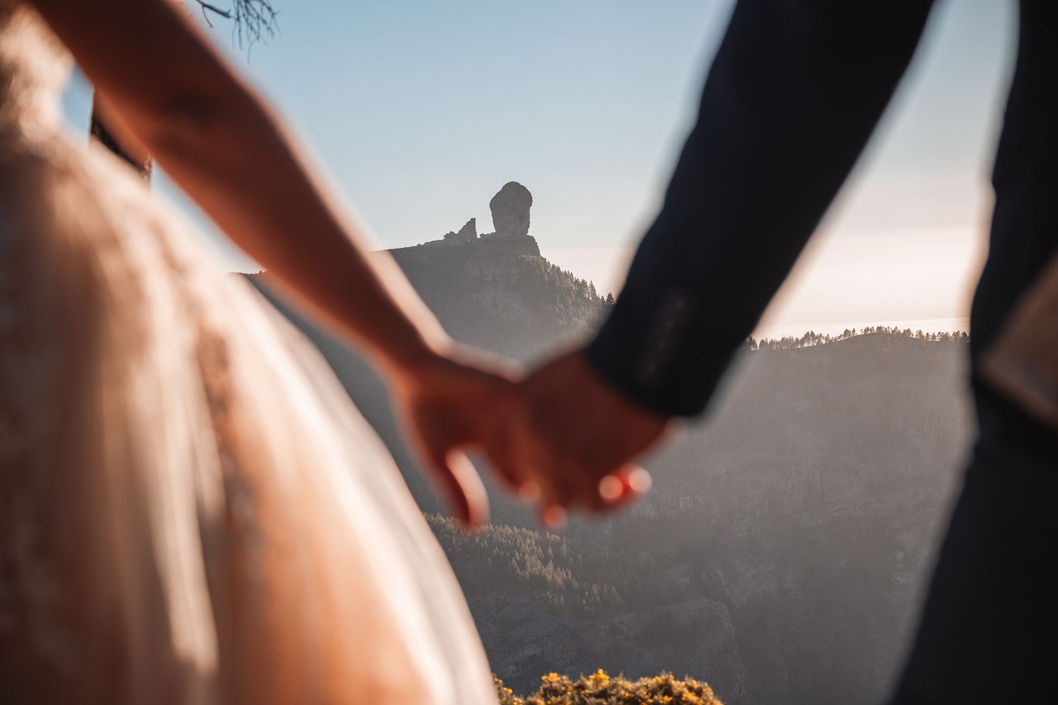 A silhouetted wedding scene against a dramatic mountain sunset backdrop.