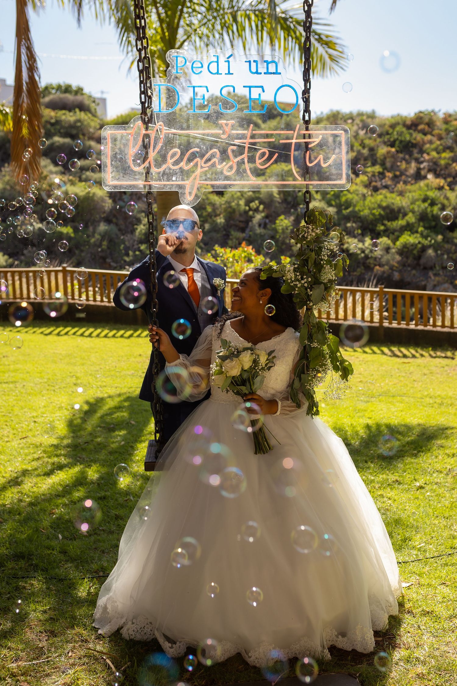 Wedding couple surrounded by floating bubbles during outdoor celebration.