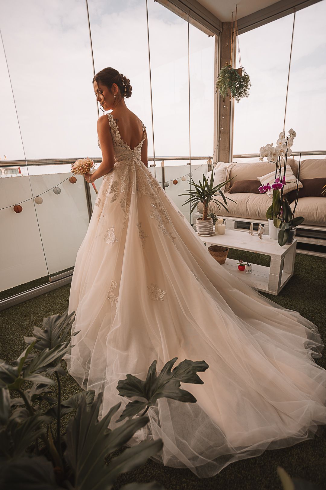 Flowing white wedding gown with dramatic train photographed on an outdoor terrace.