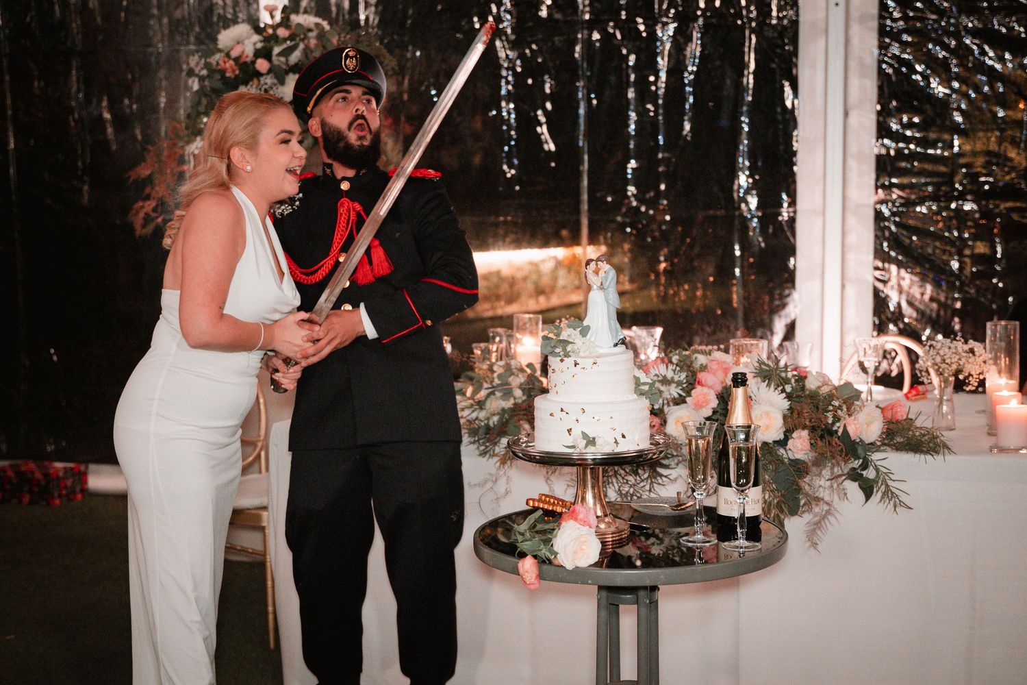 Couple cutting their wedding cake together with a ceremonial sword.