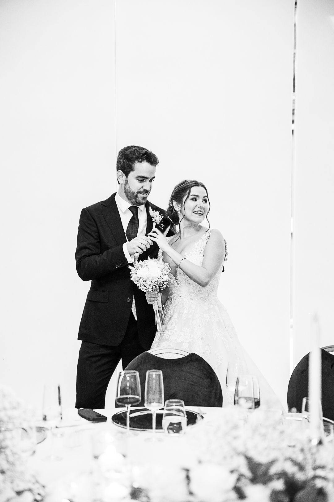 Black and white wedding reception photo showing elegant table settings and decor.