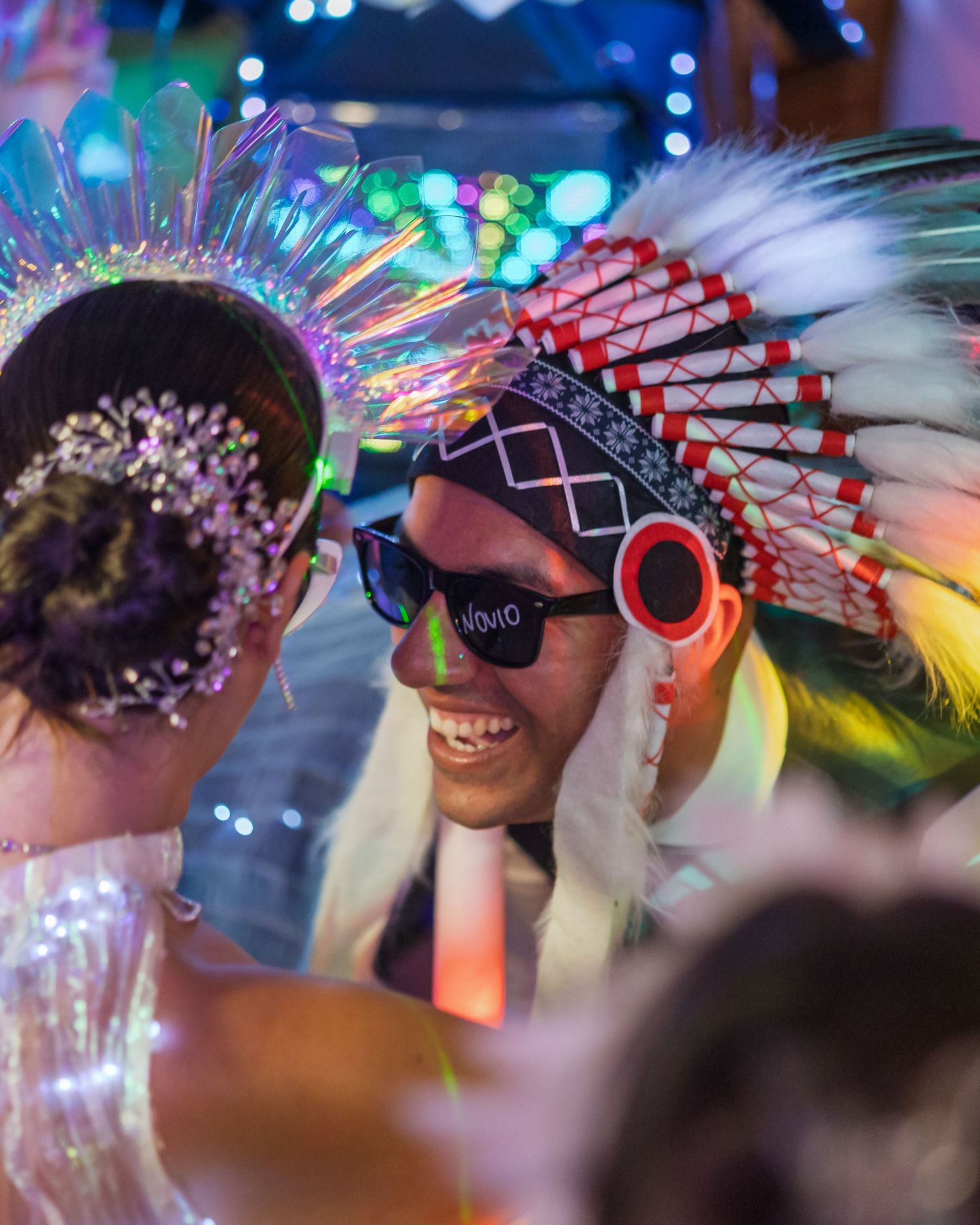 Wedding party wearing colorful LED headdresses and sunglasses during reception celebration.