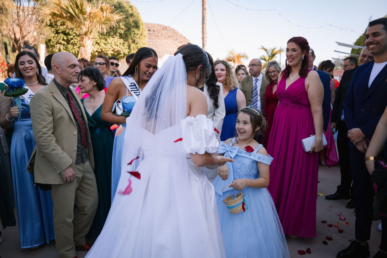 Wedding party and guests gathered outdoors for flower petal toss celebration.