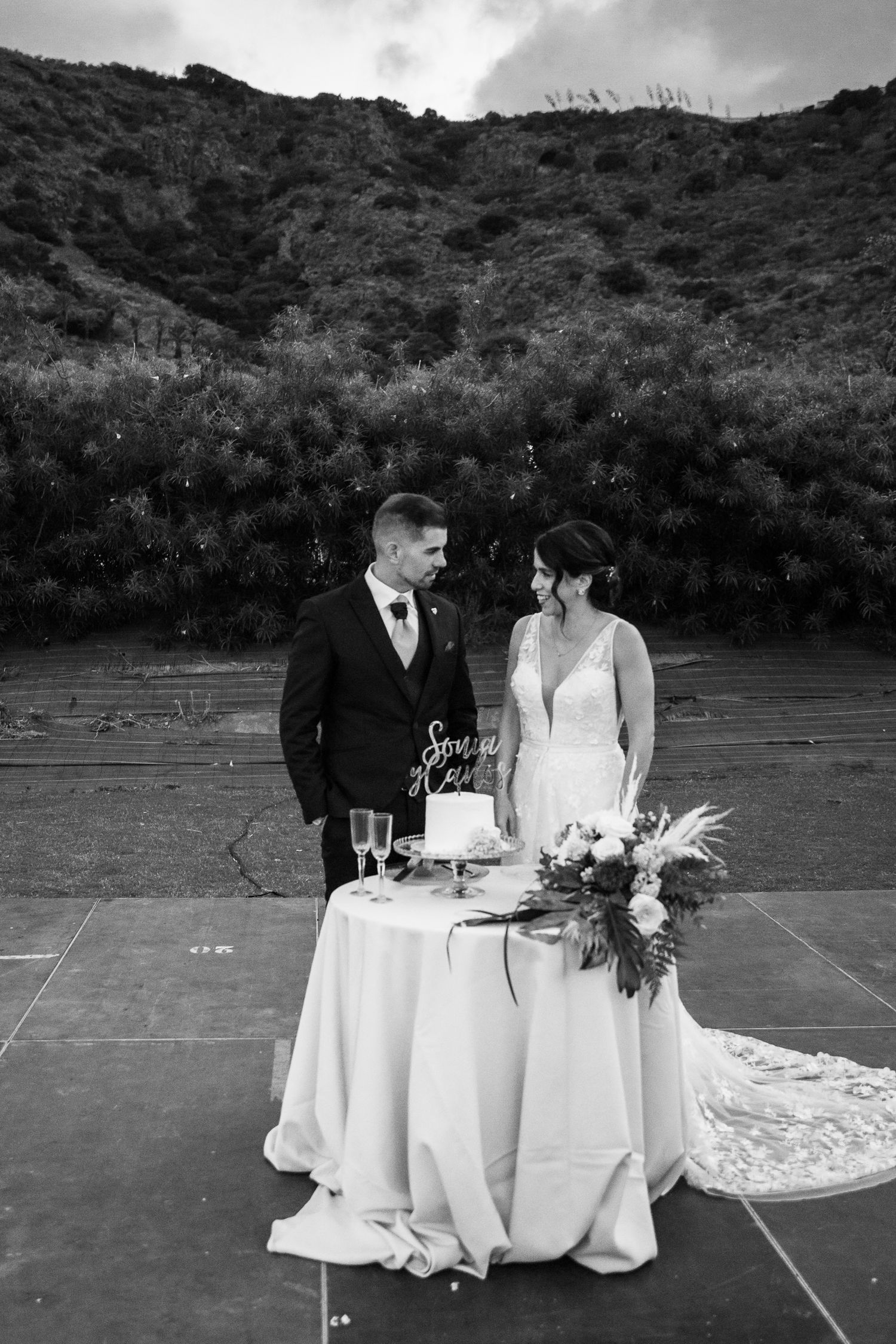 Black and white photo of sweetheart table setup with mountain backdrop.