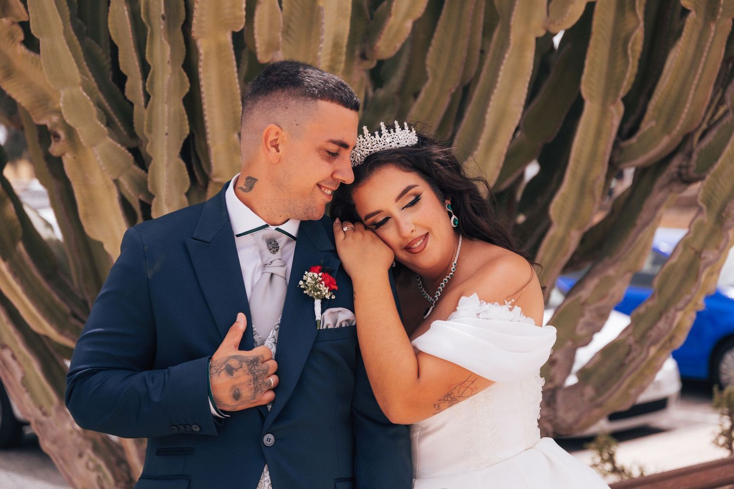 Romantic wedding couple embracing under tree branches in outdoor setting.