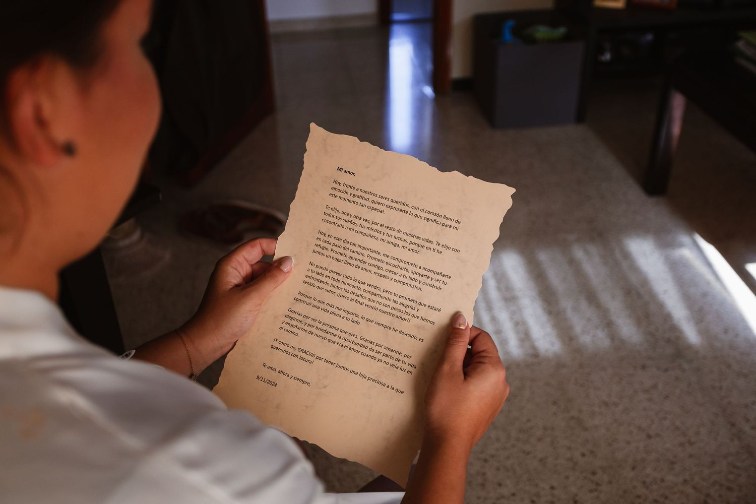 A close-up view of hands holding paper documents in a dark setting.