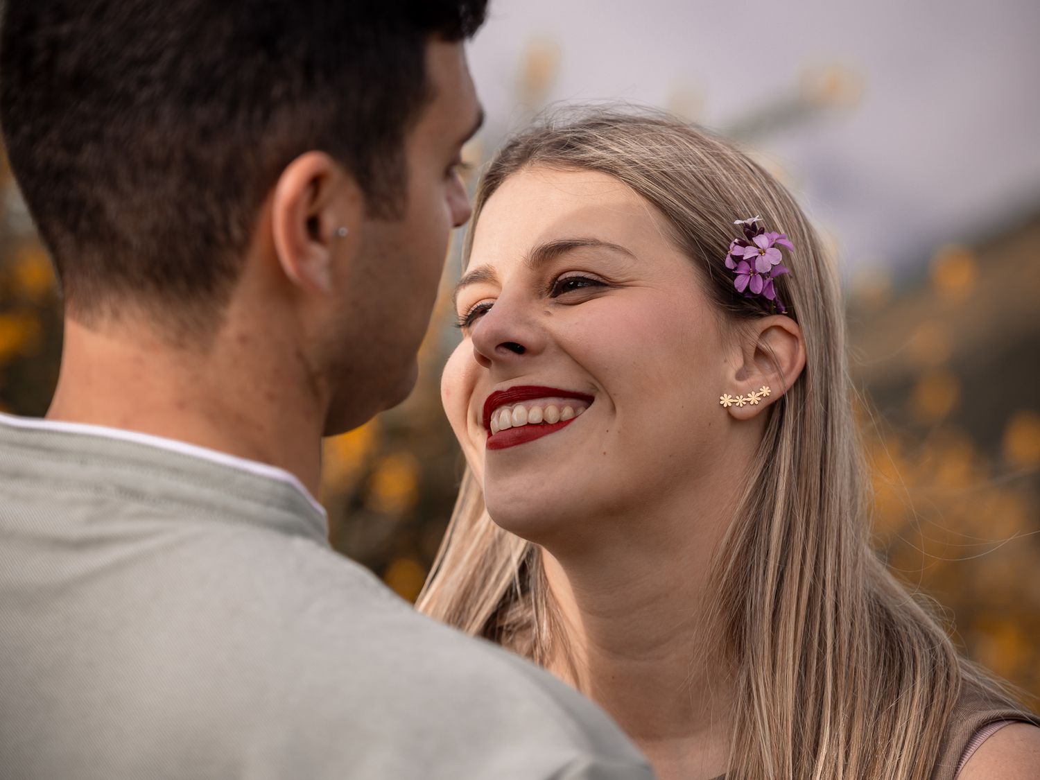 Close-up shot of people laughing together among yellow wildflowers in natural lighting.