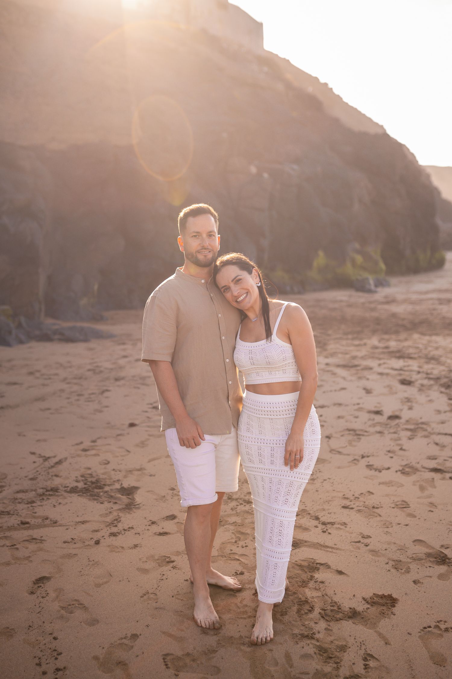 Sunset beach photoshoot with golden light illuminating a couple's tender moments.