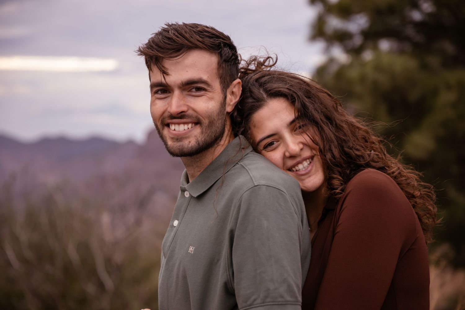 Couple enjoying a tender moment against a mountain landscape at sunset.