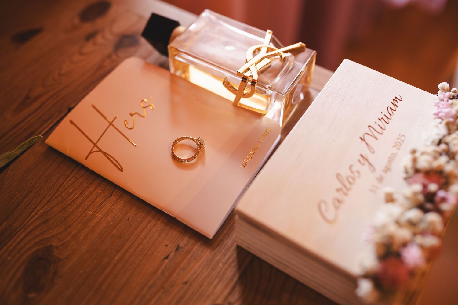 Wedding stationery and rings artfully arranged on wooden surface with soft lighting.