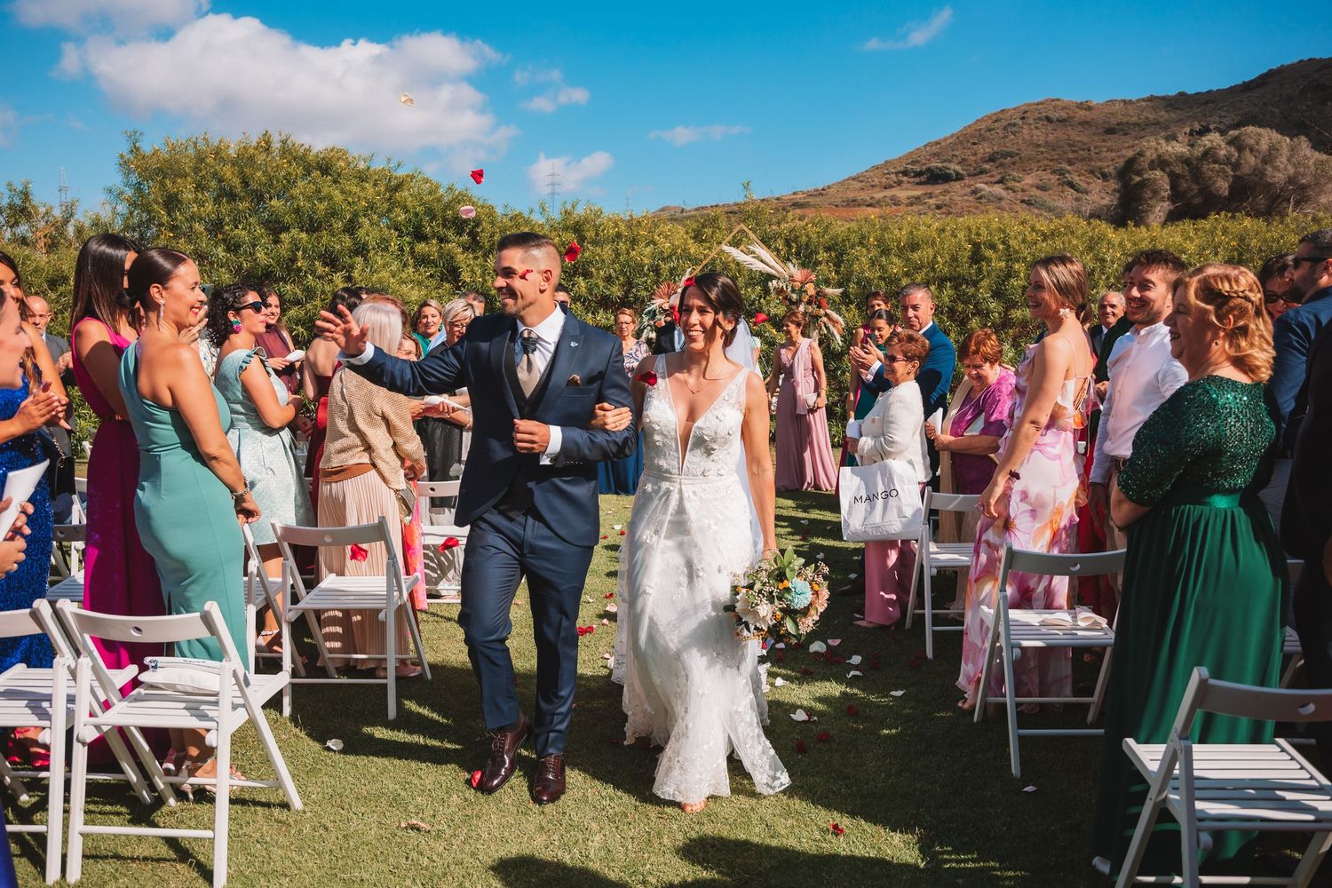 Outdoor wedding ceremony setup with white chairs and mountain views.