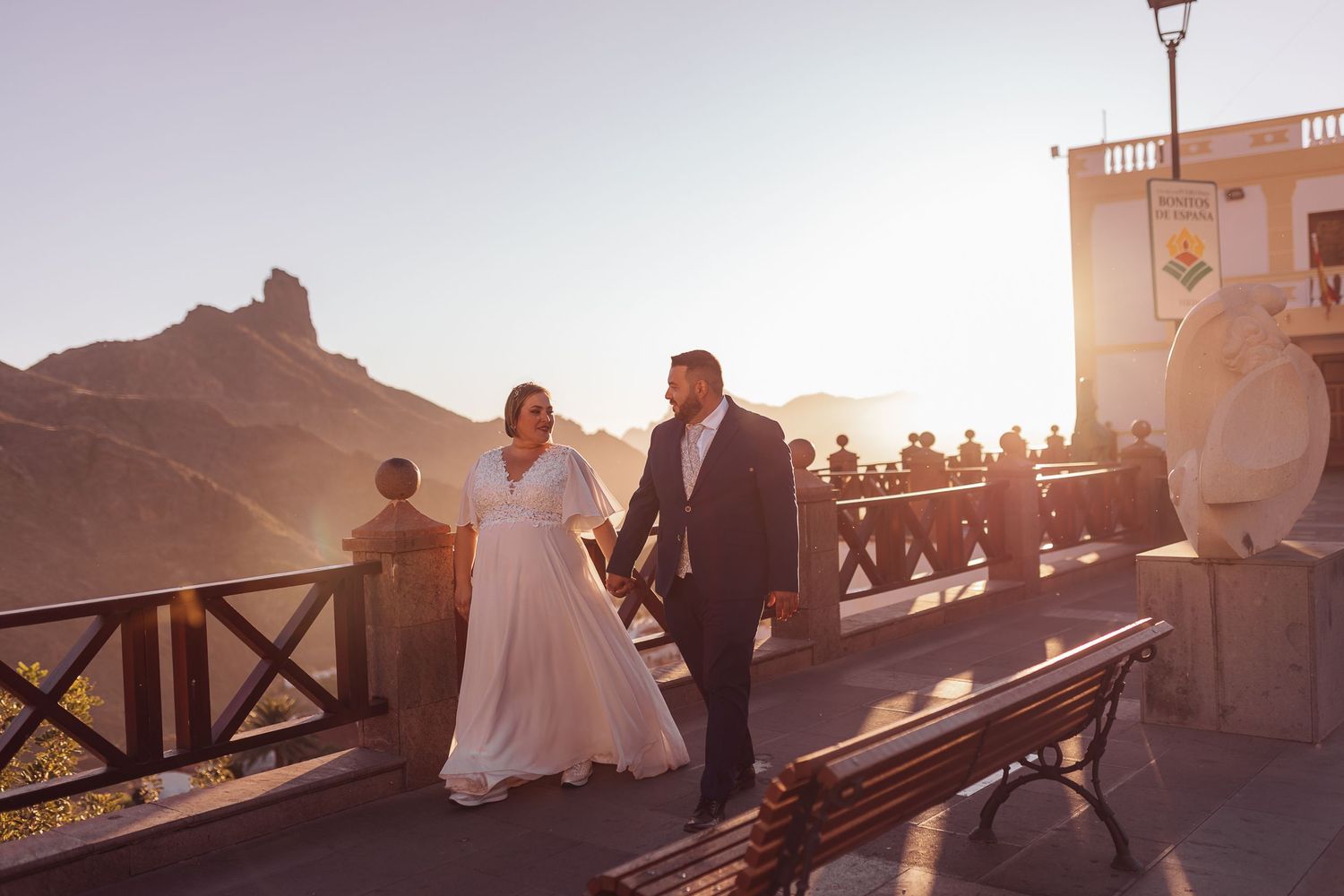A couple walks along a scenic overlook during golden hour at their destination wedding.