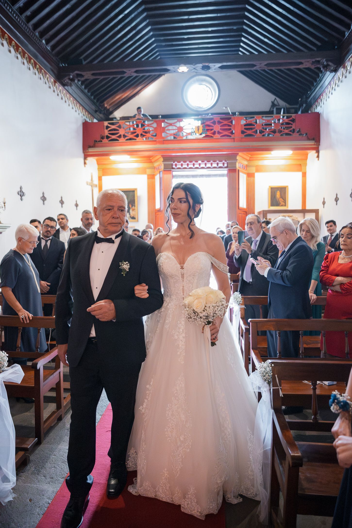 Traditional church wedding ceremony with elegant decor and white pews.