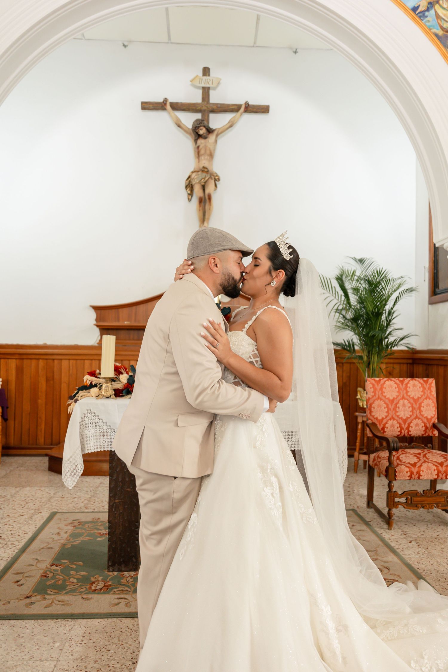 Newlyweds share their first kiss as a married couple inside a beautiful church with wooden accents.