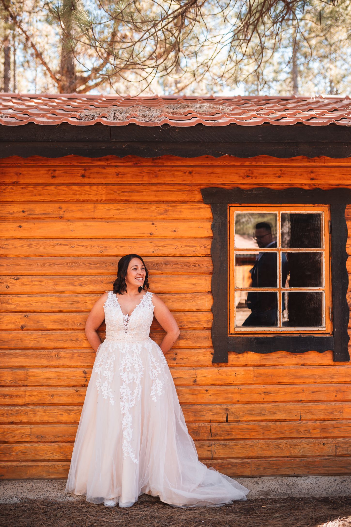 White wedding dress contrasting against rustic wooden cabin exterior.