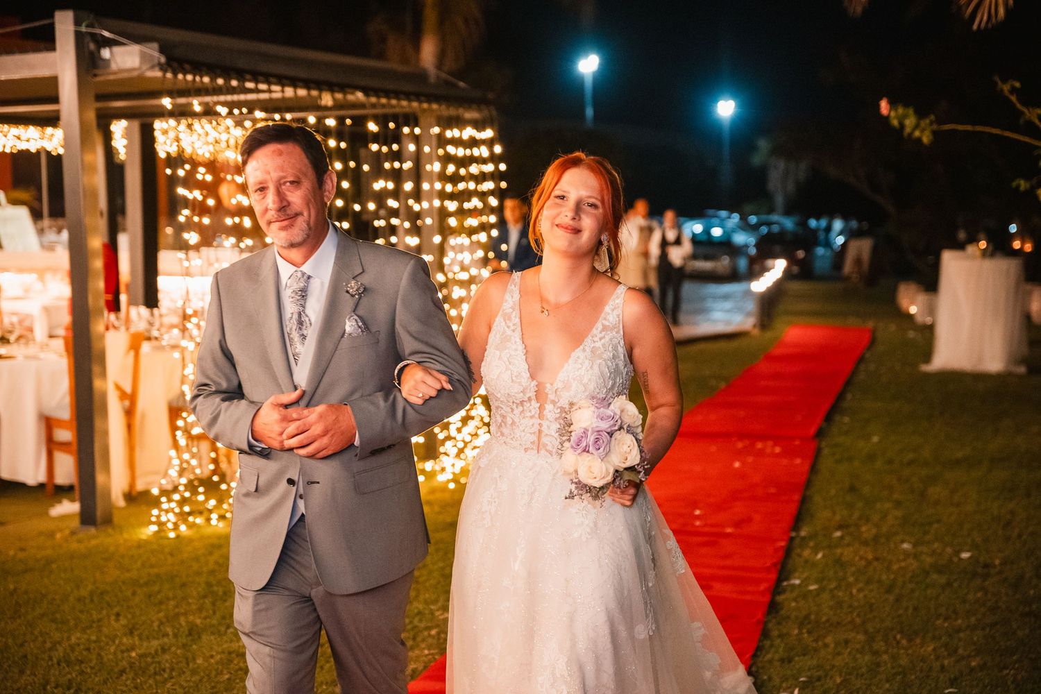 Wedding celebration at night with red carpet and string lights creating a romantic ambiance.