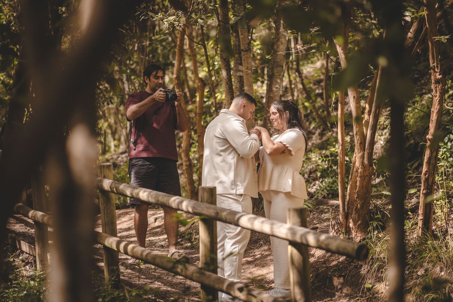 Couple exchanging vows in a lush forest setting, officiated by a man, during an intimate outdoor wedding ceremony.