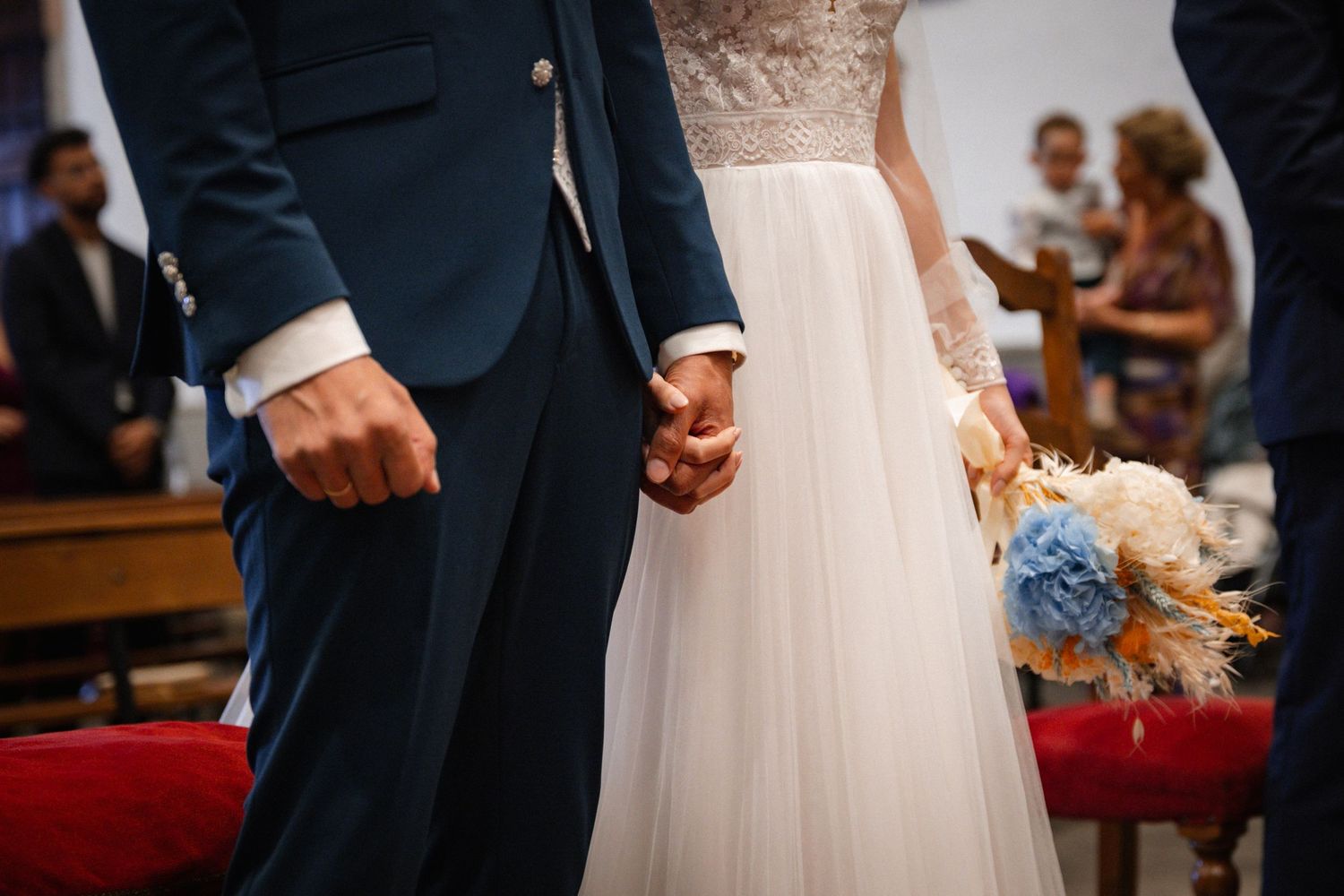 A close-up of formal wedding attire showing a navy suit next to a white dress.
