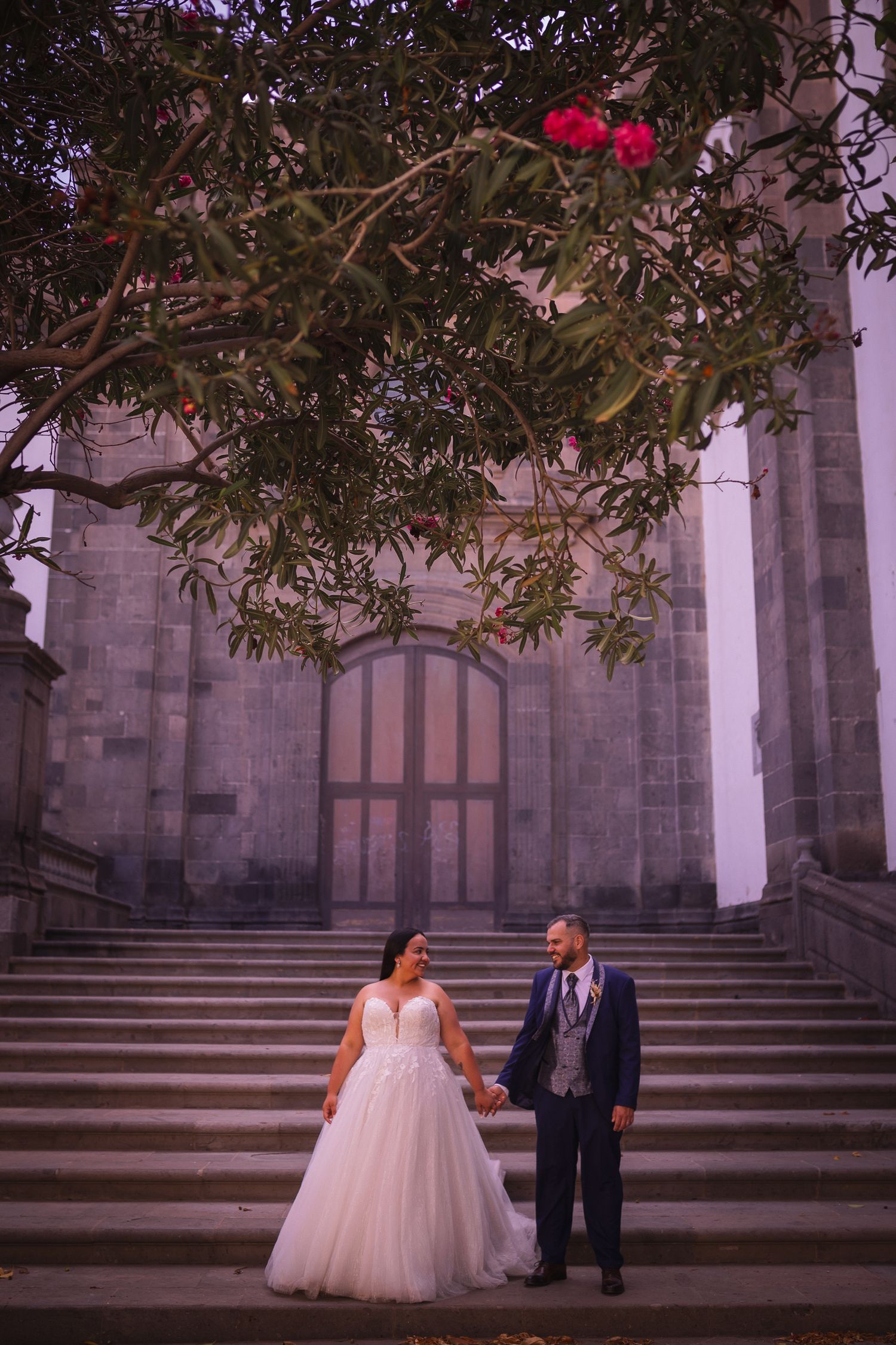 Wedding photography at stone church steps with blooming bougainvillea flowers.