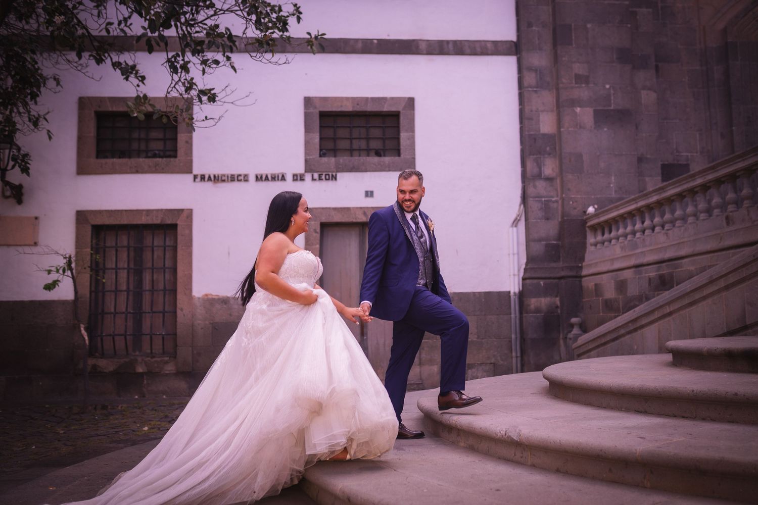 Wedding photoshoot in front of a historic stone building with dramatic lighting.