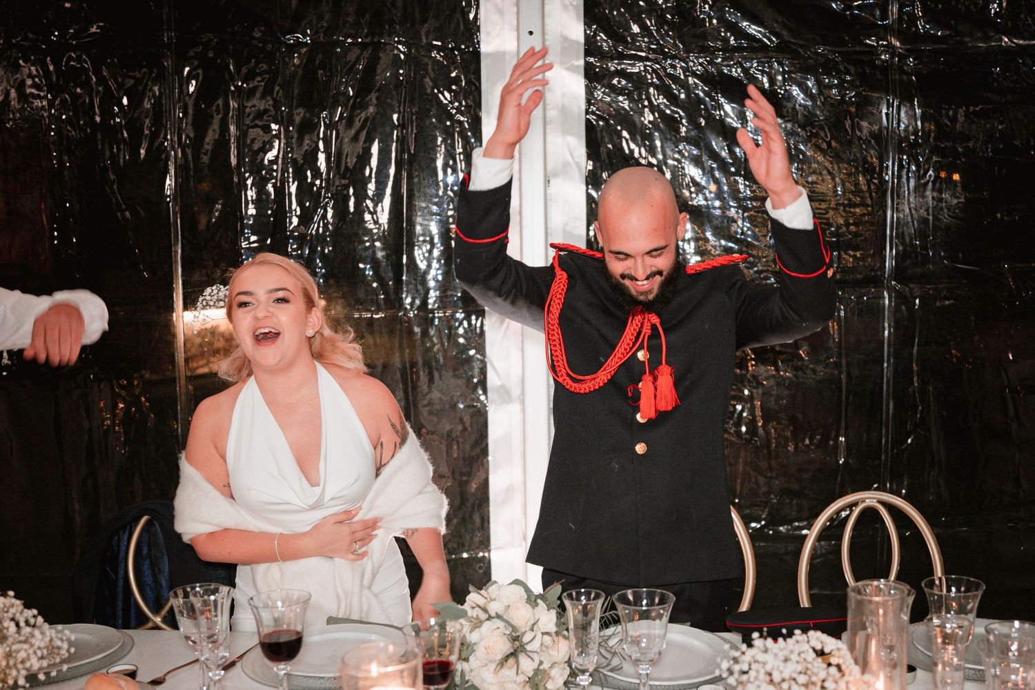 Couple showing excitement at their wedding reception table with festive decorations.