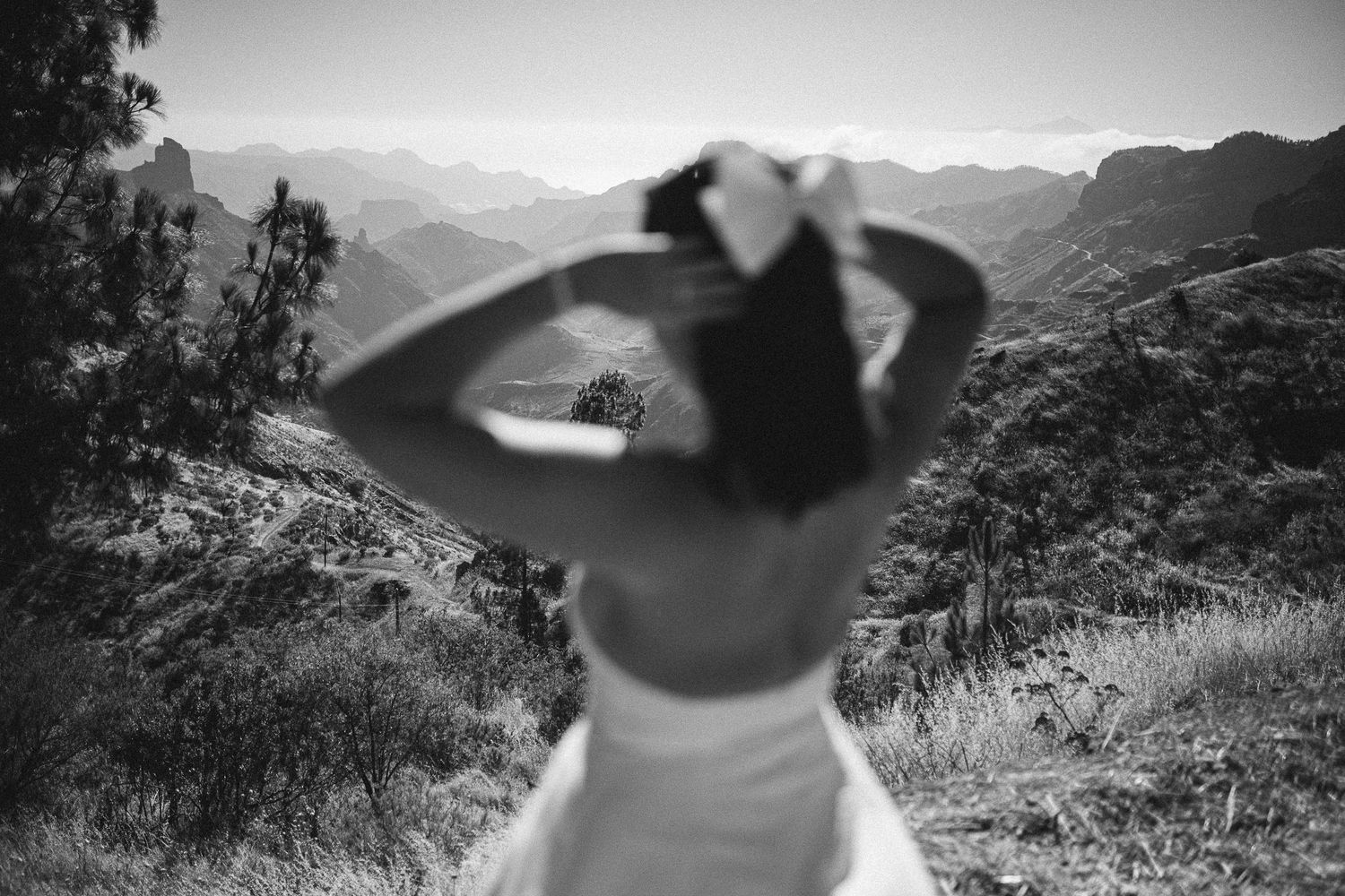 Black and white photo showing a mountain landscape through a hand-formed circle frame.