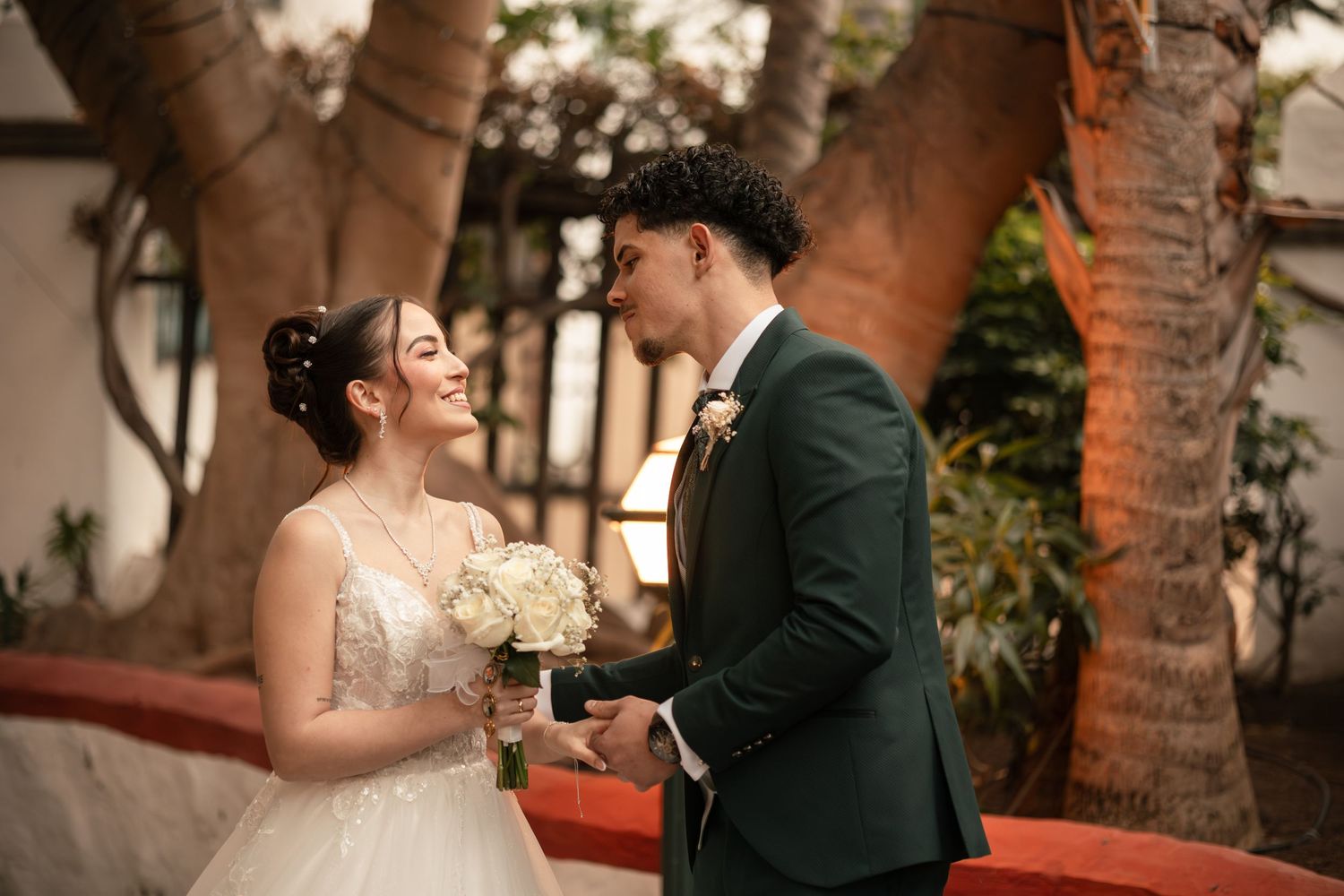 A romantic couple shares a tender moment during their wedding celebration in an elegant indoor venue with warm lighting.