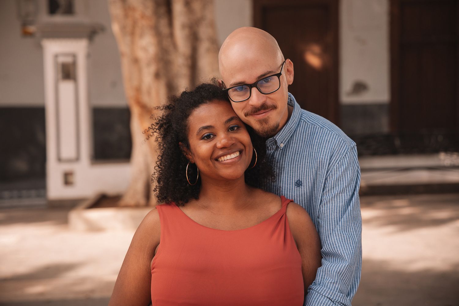 Couple poses for casual engagement photos in an urban setting.