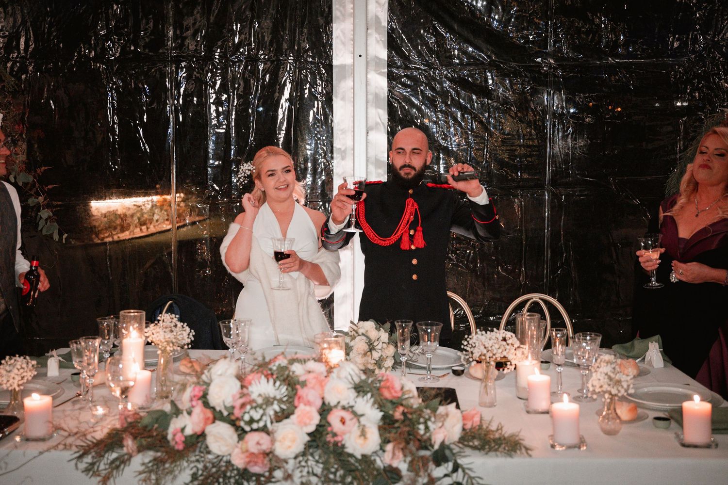 Wedding couple celebrating at their reception table decorated with pink floral centerpieces and candles.